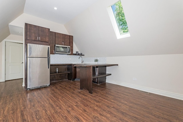 kitchen featuring a kitchen bar, appliances with stainless steel finishes, dark hardwood / wood-style floors, and vaulted ceiling with skylight