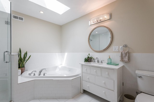 full bathroom featuring a skylight, vanity, independent shower and bath, tile patterned flooring, and toilet