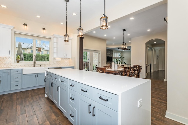 kitchen with a center island, decorative light fixtures, dark wood-type flooring, and sink