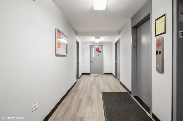 hallway with elevator and light hardwood / wood-style flooring