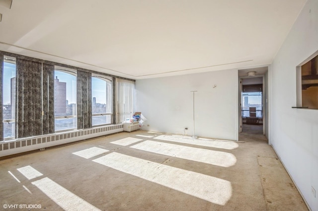 unfurnished room featuring a baseboard radiator and a healthy amount of sunlight