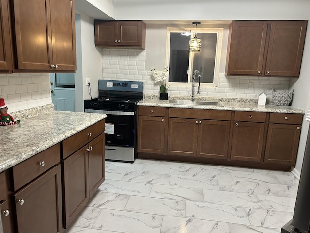 kitchen with decorative light fixtures, stainless steel stove, tasteful backsplash, and sink