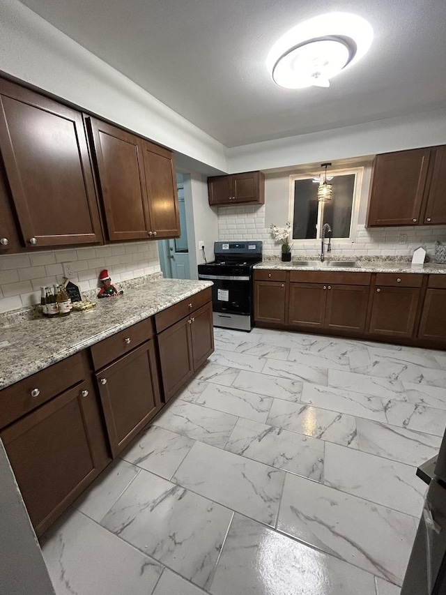 kitchen featuring sink, stainless steel range, tasteful backsplash, dark brown cabinets, and light stone counters