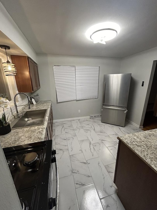 kitchen featuring black stove, stainless steel refrigerator, and sink