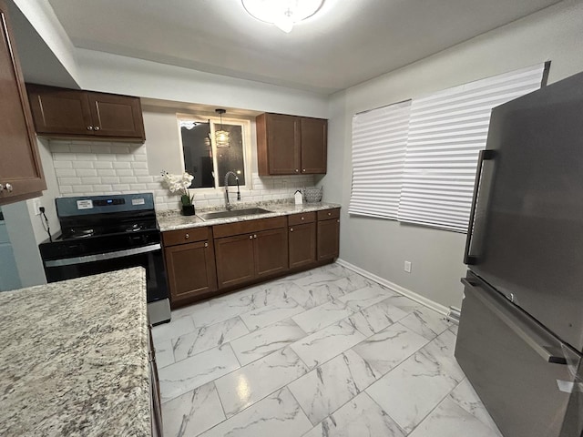 kitchen with backsplash, refrigerator, sink, gas range, and light stone counters