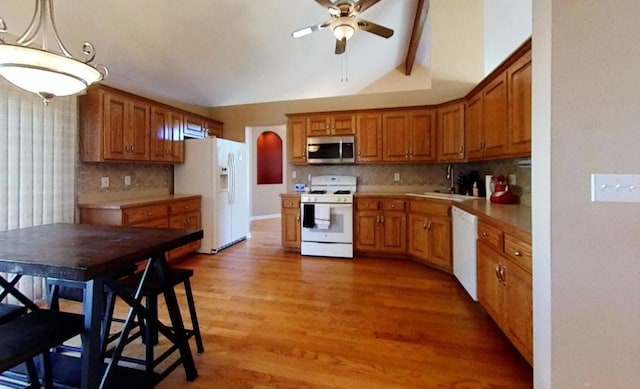 kitchen with white appliances, lofted ceiling with beams, sink, hardwood / wood-style flooring, and decorative light fixtures