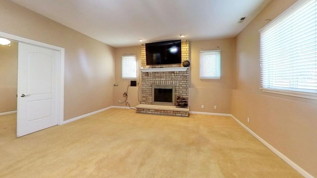 unfurnished living room with carpet flooring, a brick fireplace, and plenty of natural light