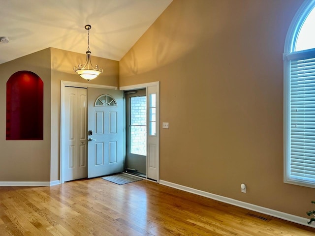 foyer entrance with high vaulted ceiling, a healthy amount of sunlight, and light hardwood / wood-style floors