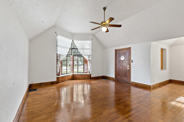 unfurnished living room featuring vaulted ceiling, ceiling fan, wood-type flooring, and a textured ceiling