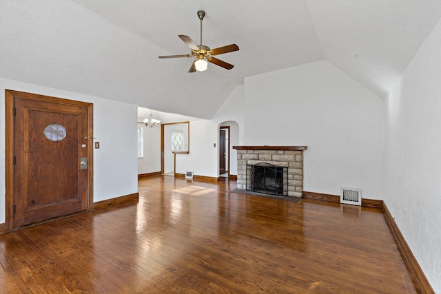 unfurnished living room featuring ceiling fan with notable chandelier, a stone fireplace, dark wood-type flooring, and vaulted ceiling