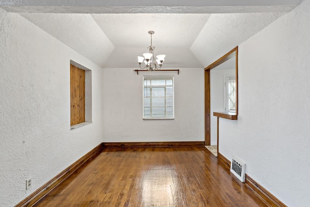 spare room featuring dark wood-type flooring, lofted ceiling, and a notable chandelier