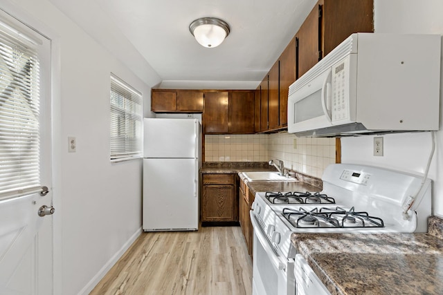 kitchen featuring white appliances, backsplash, light hardwood / wood-style flooring, and sink