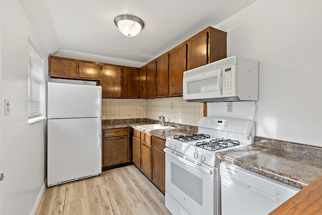 kitchen with decorative backsplash, white appliances, sink, light hardwood / wood-style floors, and lofted ceiling