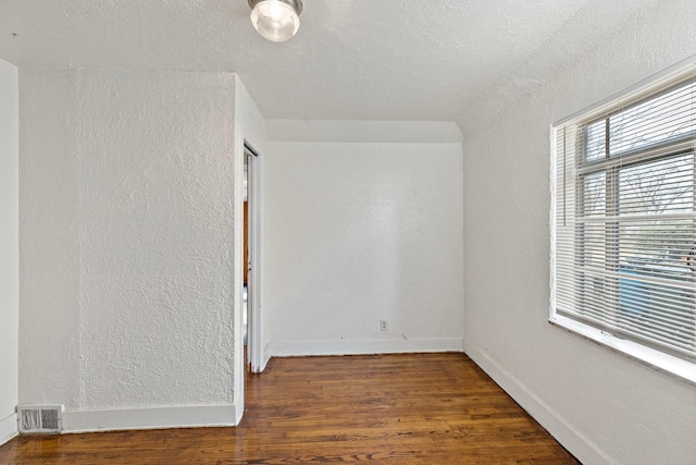 unfurnished room with dark hardwood / wood-style flooring and a textured ceiling