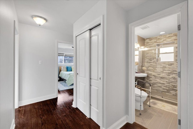 hallway with sink, dark wood-type flooring, and tile walls