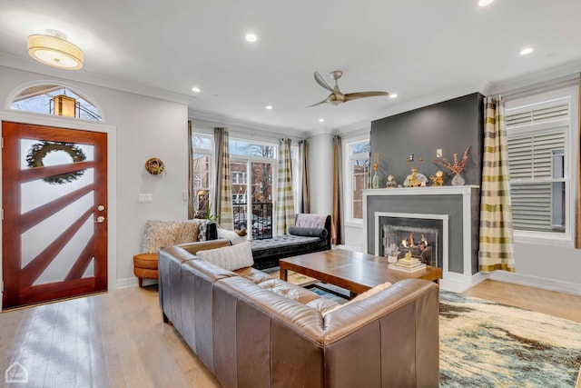 living room with crown molding, ceiling fan, and light wood-type flooring