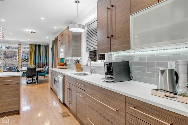 kitchen featuring tasteful backsplash, decorative light fixtures, sink, and light wood-type flooring