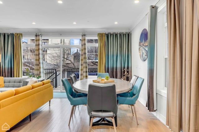 dining space with crown molding, plenty of natural light, and light wood-type flooring