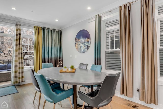 dining area with crown molding and light hardwood / wood-style flooring