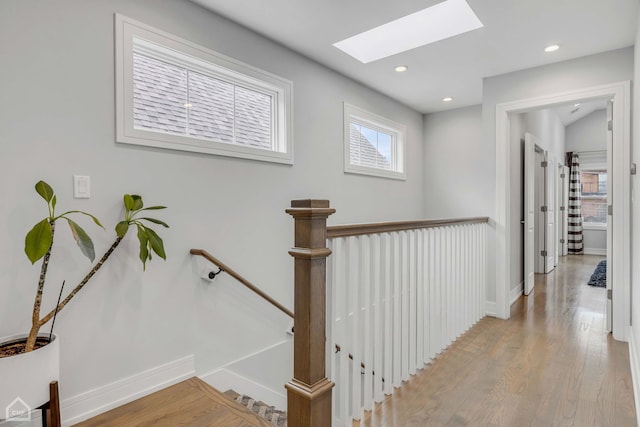 hall with light hardwood / wood-style flooring and a skylight