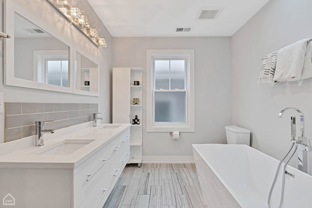 bathroom with toilet, vanity, a tub, hardwood / wood-style floors, and decorative backsplash