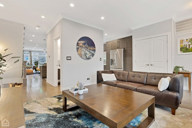 living room with crown molding and light hardwood / wood-style flooring