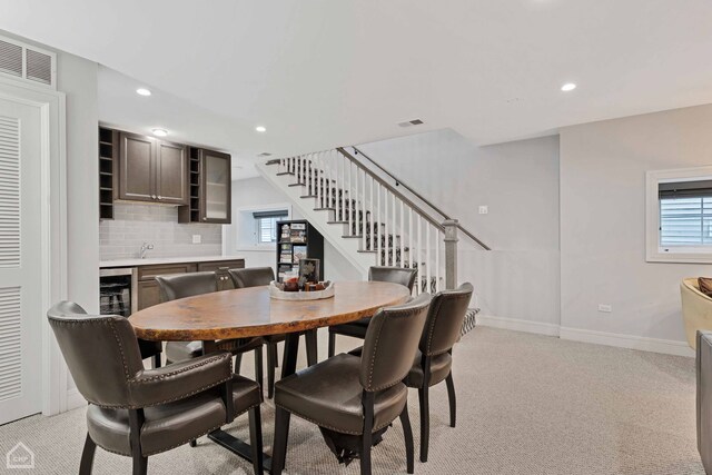 kitchen featuring dark brown cabinetry, beverage cooler, sink, and decorative backsplash