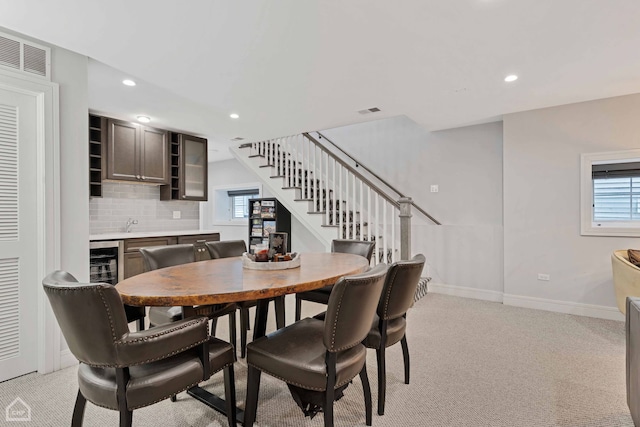 carpeted dining area featuring wine cooler and a healthy amount of sunlight