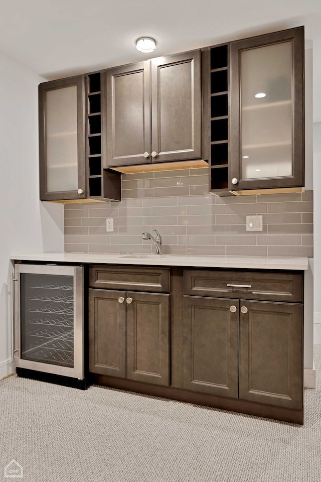 kitchen featuring wine cooler, tasteful backsplash, sink, and dark brown cabinets