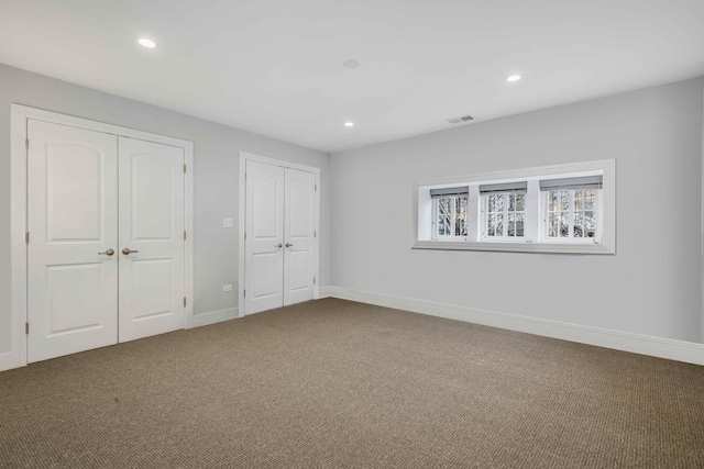 unfurnished bedroom featuring two closets and carpet flooring