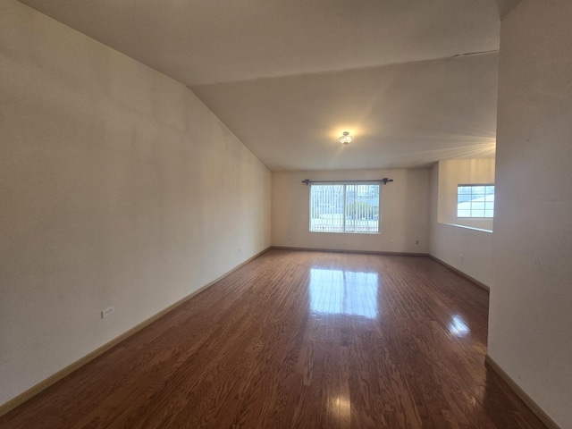 empty room with dark wood-type flooring and lofted ceiling