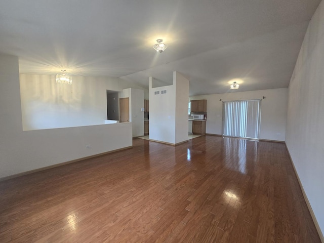 unfurnished living room featuring a chandelier, wood-type flooring, and lofted ceiling