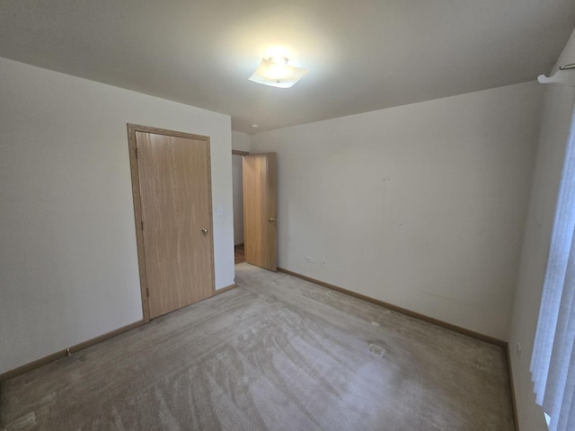 unfurnished bedroom with light colored carpet and a closet