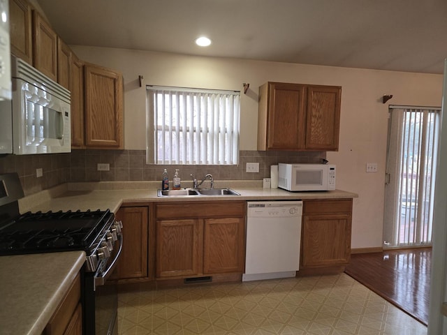 kitchen with backsplash, sink, white appliances, and light wood-type flooring