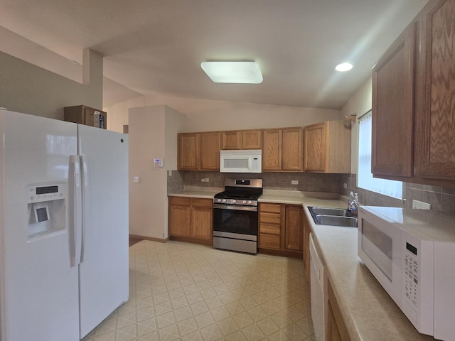 kitchen with decorative backsplash, white appliances, sink, and vaulted ceiling