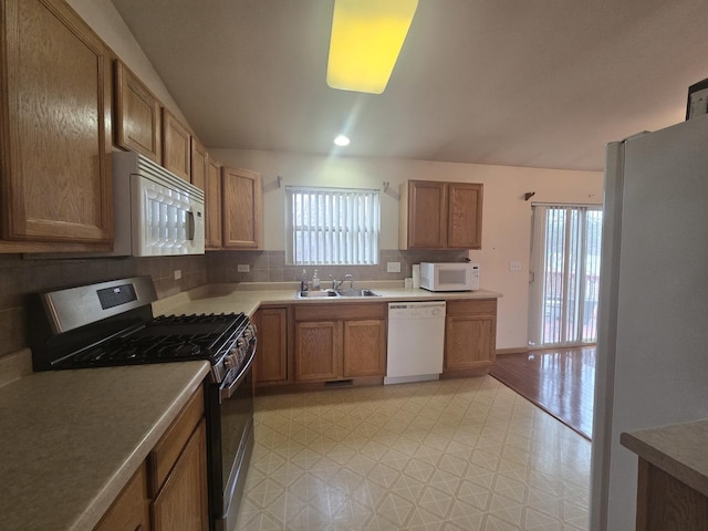 kitchen featuring white appliances, tasteful backsplash, and sink