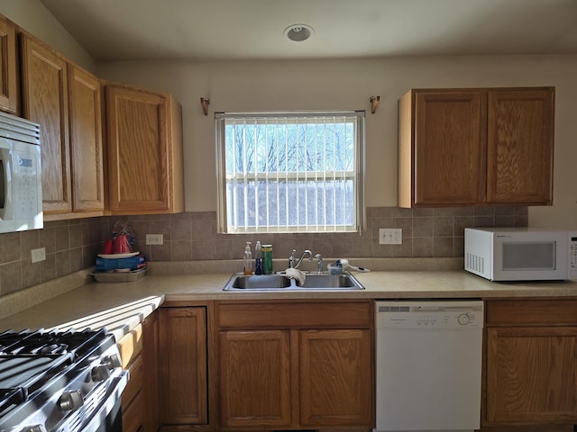 kitchen with backsplash, white appliances, and sink