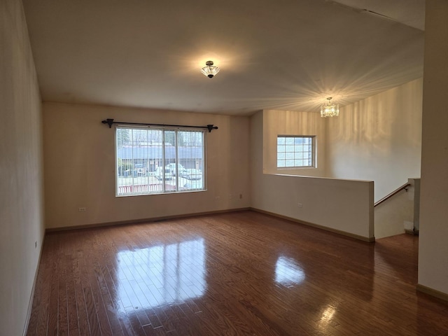 empty room with hardwood / wood-style floors, a notable chandelier, and a wealth of natural light