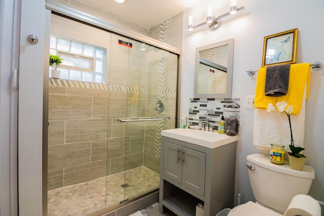 bathroom featuring an enclosed shower, vanity, toilet, and backsplash