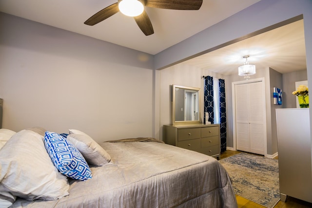 bedroom with ceiling fan with notable chandelier, hardwood / wood-style flooring, and a closet