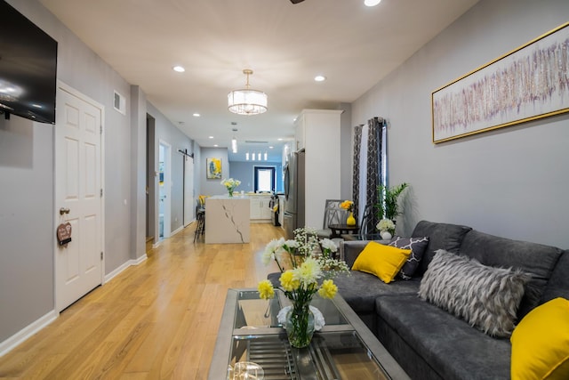 living room with light hardwood / wood-style floors and an inviting chandelier