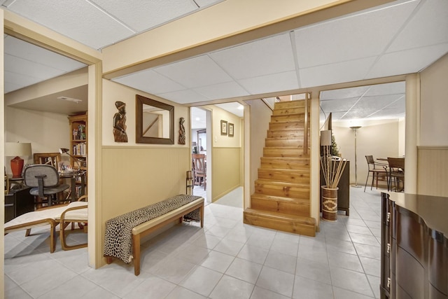 interior space with stairs, light tile patterned floors, and a paneled ceiling