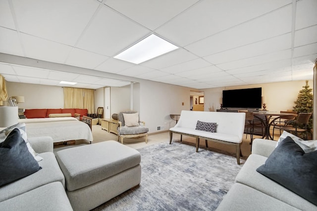 living area featuring carpet flooring, a paneled ceiling, and baseboards