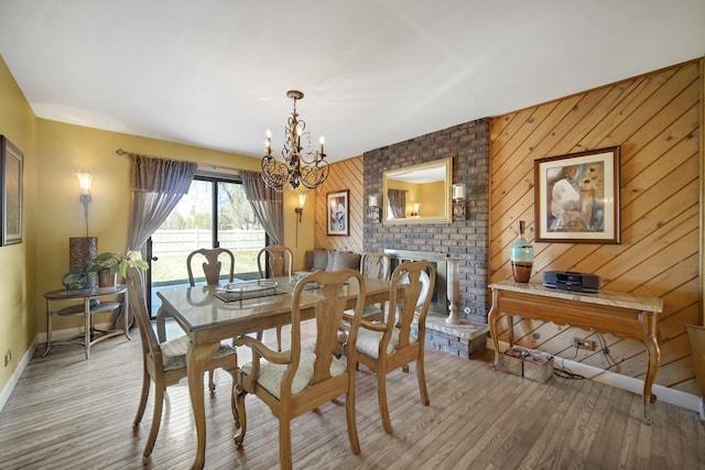 dining room with light hardwood / wood-style floors, an inviting chandelier, and wood walls