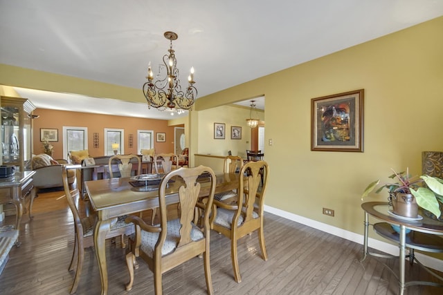 dining space featuring dark hardwood / wood-style flooring and an inviting chandelier