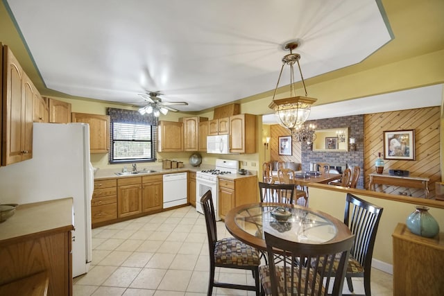 kitchen with wood walls, white appliances, ceiling fan with notable chandelier, sink, and decorative light fixtures