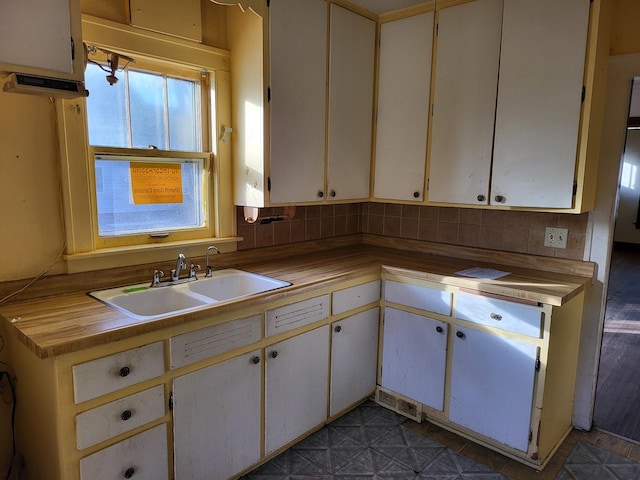 kitchen featuring decorative backsplash, white cabinetry, and sink