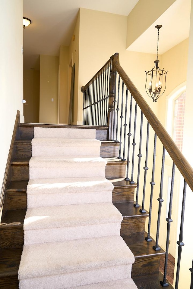 stairway featuring hardwood / wood-style floors and a chandelier