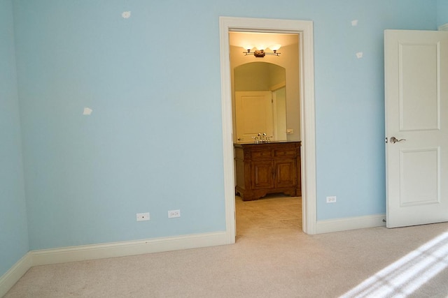 unfurnished bedroom with light colored carpet, sink, and connected bathroom