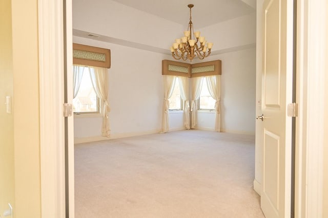 carpeted empty room featuring an inviting chandelier